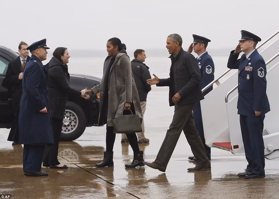 Ông Obama và Đệ nhất phu nhân Michelle bắt tay chào các trợ tá đang đứng đón họ ở sân bay. Ảnh Daily Mail