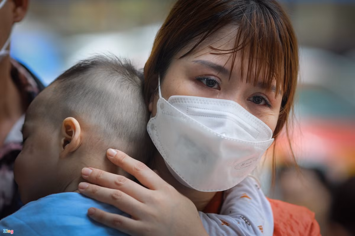 Chị Phương Thảo (30 tuổi, TP Thủ Đức) bật khóc khi chờ hơn 2 giờ chưa thể đưa con vào phòng khám. Người phụ nữ đến bệnh viện từ lúc 7h nhưng đến hơn 9h30, các thủ tục đăng ký vẫn chưa làm xong do quá đông phụ huynh đưa con đến khám. Do con trai sốt đến 40 độ C, chị Thảo lo lắng, vừa ôm con vừa khóc.