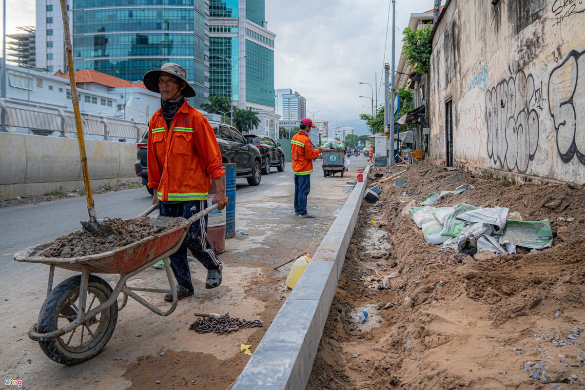 Phía bên phải cầu, mặt đường Tôn Đức Thắng hướng về quận 1, công nhân đang thi công lát gạch nền, tái lập hoàn trả hiện trạng tuyến đường.