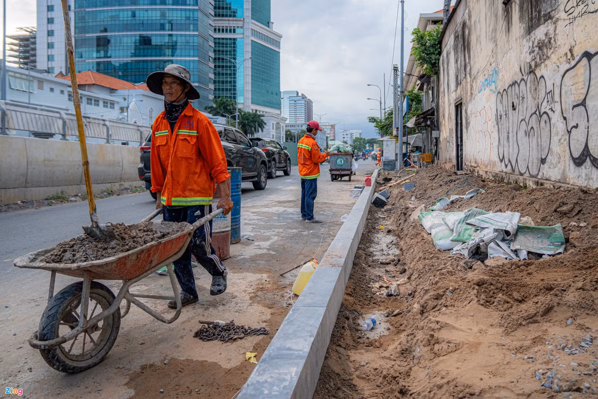 Phía bên phải cầu, mặt đường Tôn Đức Thắng hướng về quận 1, công nhân đang thi công lát gạch nền, tái lập hoàn trả hiện trạng tuyến đường.