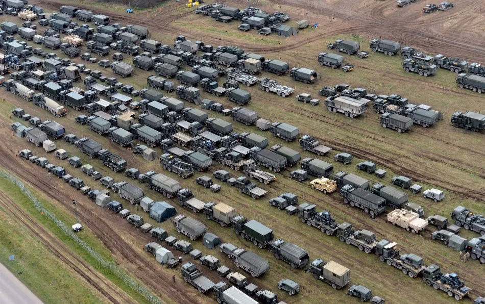 Các xe ô tô chở quân, kéo pháo, xe phục vụ nằm hàng dài tại khu đất trong thao trường.