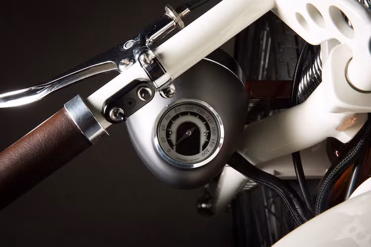 Bên dưới tay lái gập về hai bên bình xăng là đèn pha từ xe Vespa cổ, kèm theo lỗ khoét để gắn đồng hồ. Tuy nhiên, đồng hồ của xe là loại hiện đại do hãng Motogadget cung cấp.