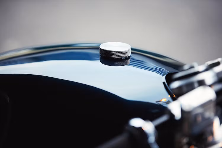 Màu sơn được anh chọn cũng đậm chất cổ điển nhưn rất "đàn ông" - xanh navy. Phía trên đỉnh bình xăng là một nắp xăng CNC nhôm với các rãnh xẻ tạo ma sát cực kỳ chính xác.