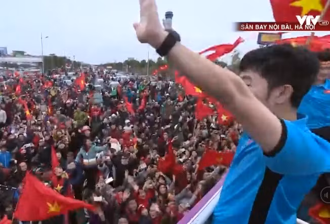 Từ xe buýt 2 tầng, Xuân Trường giơ cao tay vẫy chào hàng ngàn người hâm mộ, cổ động viên có mặt ở sân bay Nội Bài.