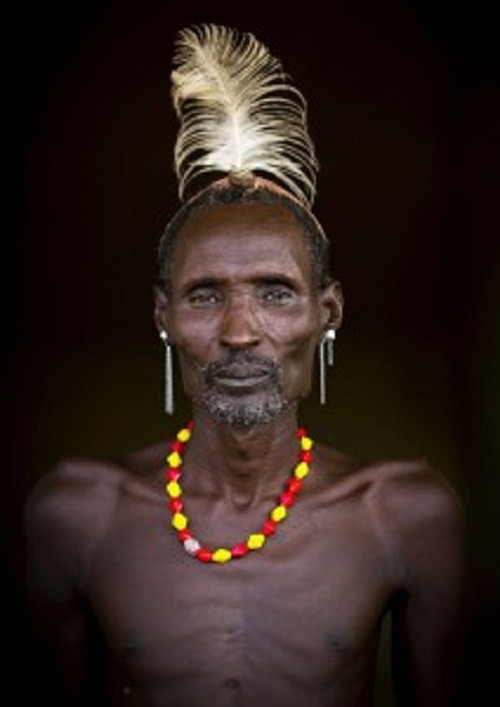 Một người đàn ông Dassanech phải đội lông đà điểu trên đầu vì lỡ giết chết một con vật nguy hiểm.