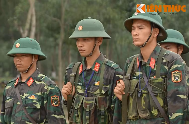 Chiến sĩ đứng chăm chú tiếp thu nội dung, trong khi trên người mang nhiều trang bị và vũ khí huấn luyện.