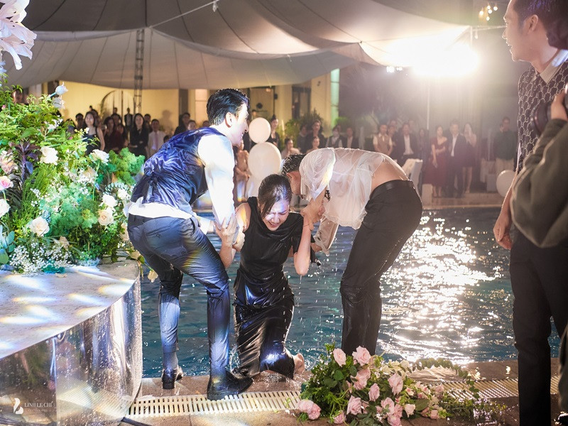 Chú rể hỗ trợ Lương Thanh lên bờ sau khi cô bị ngâm mình trong hồ bơi. Ảnh: Lê Chí Linh