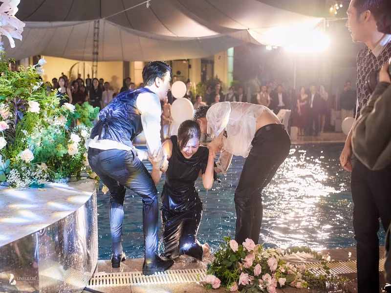 Chú rể hỗ trợ Lương Thanh lên bờ sau khi cô bị ngâm mình trong hồ bơi. Ảnh: Lê Chí Linh