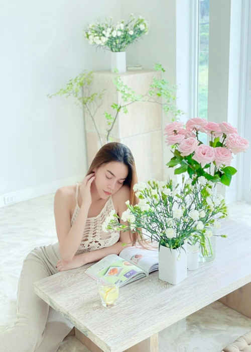 Nữ ca sĩ đọc sách thư giãn trong không gian ngập tràn hoa, cây xanh.