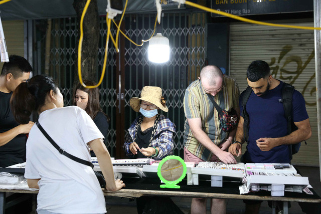 Du khách nước ngoài đến mua sắm tại chợ đêm trong tối mở cửa trở lại. Ảnh: Hoàng Hiếu-TTXVN.