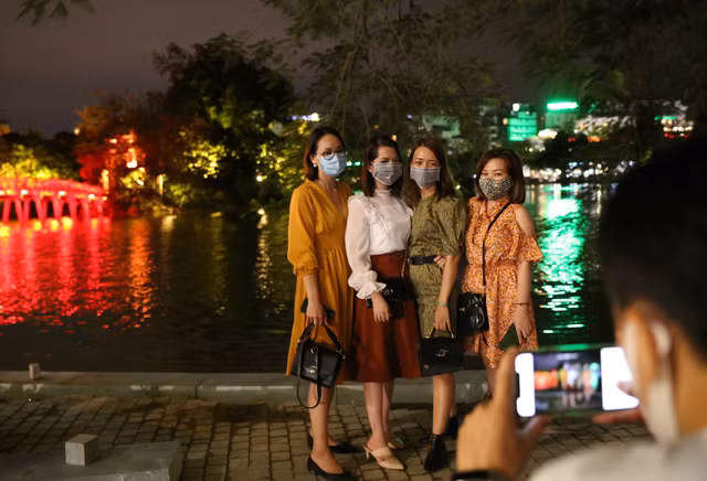 Các bạn trẻ cùng nhau chụp ảnh kỷ niệm bên hồ Hoàn Kiếm trong tối phố đi bộ mở cửa trở lại. Ảnh: Hoàng Hiếu- TTXVN.