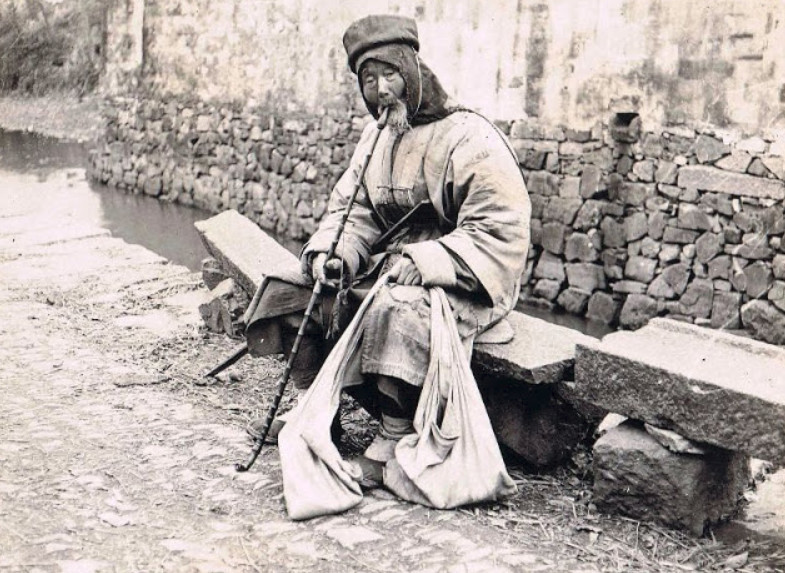 Cụ già ngồi hút thuốc ven đường. Ảnh: sohu.com.