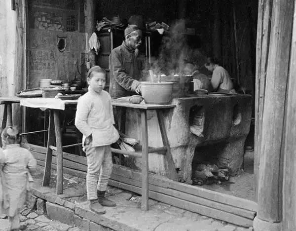 Một bé gái Trung Quốc đứng trước cửa tiệm bán đồ ăn vặt ven đường tại Hàng Châu. Ảnh: sina.com.cn. 