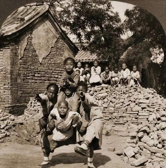 Những em bé Trung Quốc chơi đùa bên đống gạch đổ nát. Ảnh: sina.com.