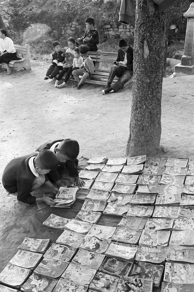 Hai cậu bé Hàn Quốc chăm chú đọc truyện bên quầy sách ven đường phố Seoul. Ảnh: sina.com.cn