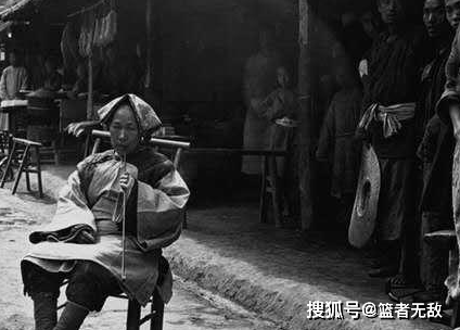 Một người phụ nữ Trung Quốc ngồi hút thuốc trước cửa nhà với đôi chân được bó gót sen. Ảnh: sohu.com