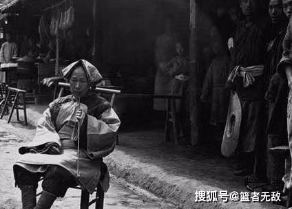 Một người phụ nữ Trung Quốc ngồi hút thuốc trước cửa nhà với đôi chân được bó gót sen. Ảnh: sohu.com