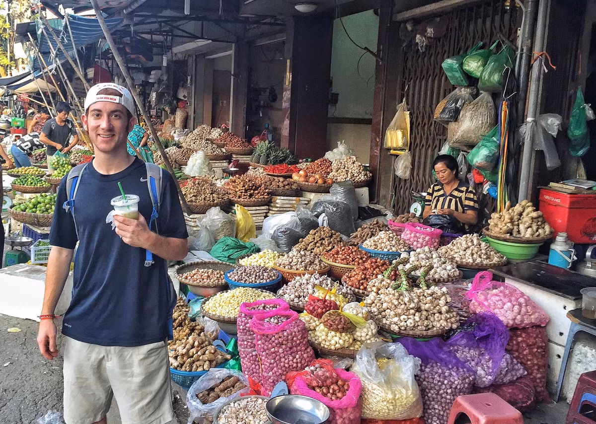 Anh Drew Binsky chụp ảnh trước một sạp hàng bán hành tỏi khô ở Việt Nam.