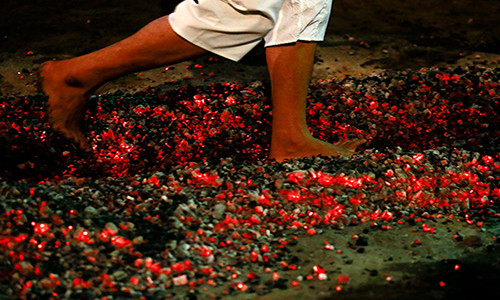 Một người dân Myanmar đi chân trần qua đống than đỏ rực ở Yangon, Myanmar.