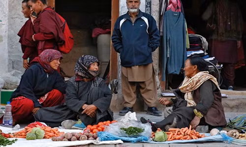 Những người dân bán rau trên vỉa hè trước một cửa hàng quần áo.