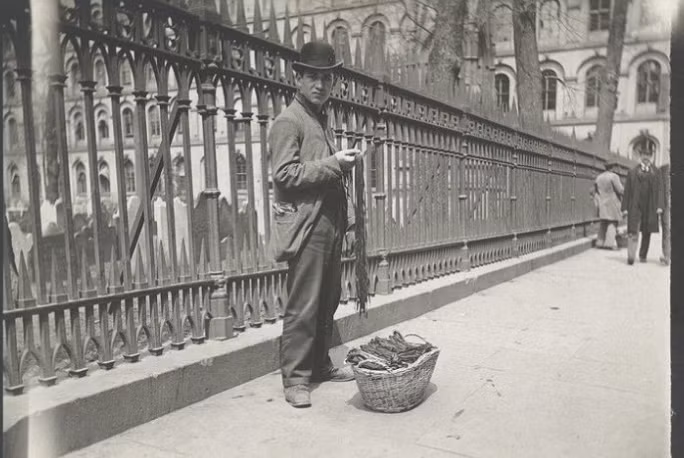 Người đàn ông bán dây giày trên vỉa hè. Được biết, năm 1897, chính quyền thành phố New York đã xây dựng 18 “tòa nhà định cư” nhằm hỗ trợ các di dân thích nghi với cuộc sống ở Mỹ.