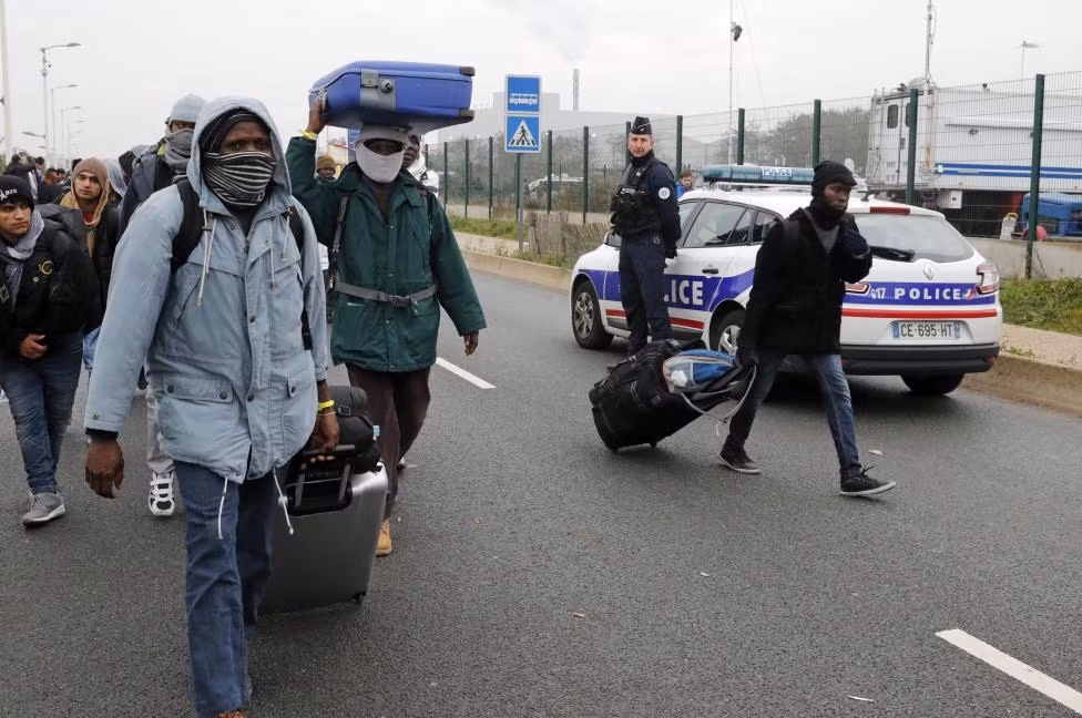 Cảnh sát Pháp quan sát những di dân khi họ bắt đầu rời khỏi trại tị nạn Jungle ở Calais hôm 24/10.