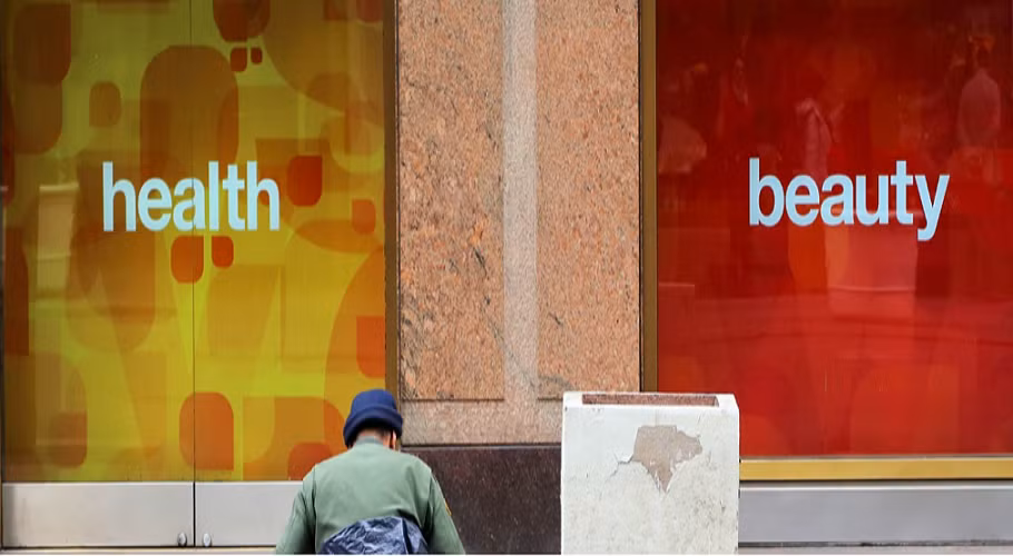 Một người vô gia cư ngồi bên vỉa hè, cạnh một cửa hàng ở thành phố New York, Mỹ. Ảnh: Philip King.