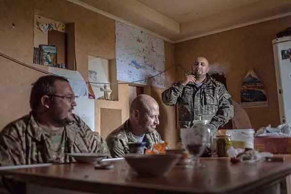 Một "tình nguyện viên" người Macedonia hút thuốc trong khi Tuna và Leshiy thảo luận về tình hình chiến sự.