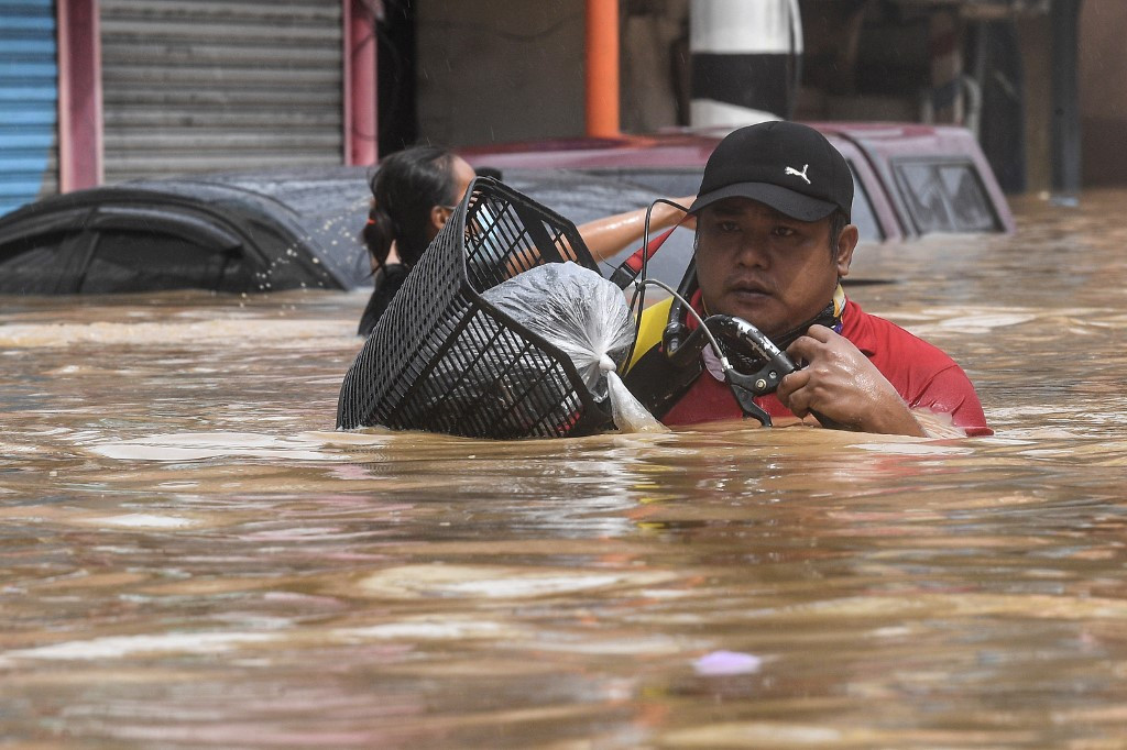 Một người dân lội nước gần đến cổ tại Marikina. Ảnh: AFP.