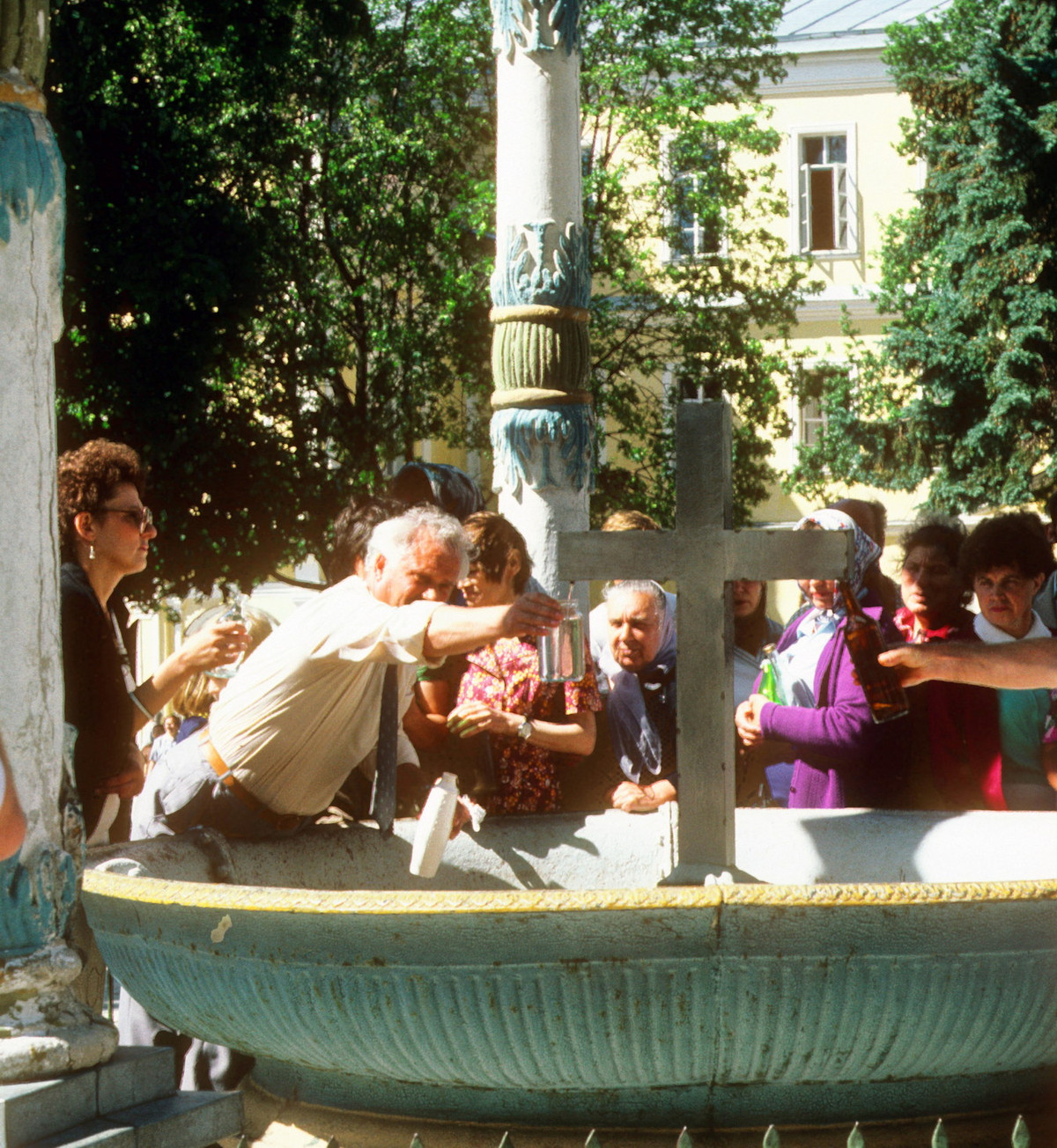 Du khách hứng nước từ vòi phun hình cây thánh giá ở Lavra Thiên Chúa Ba Ngôi.