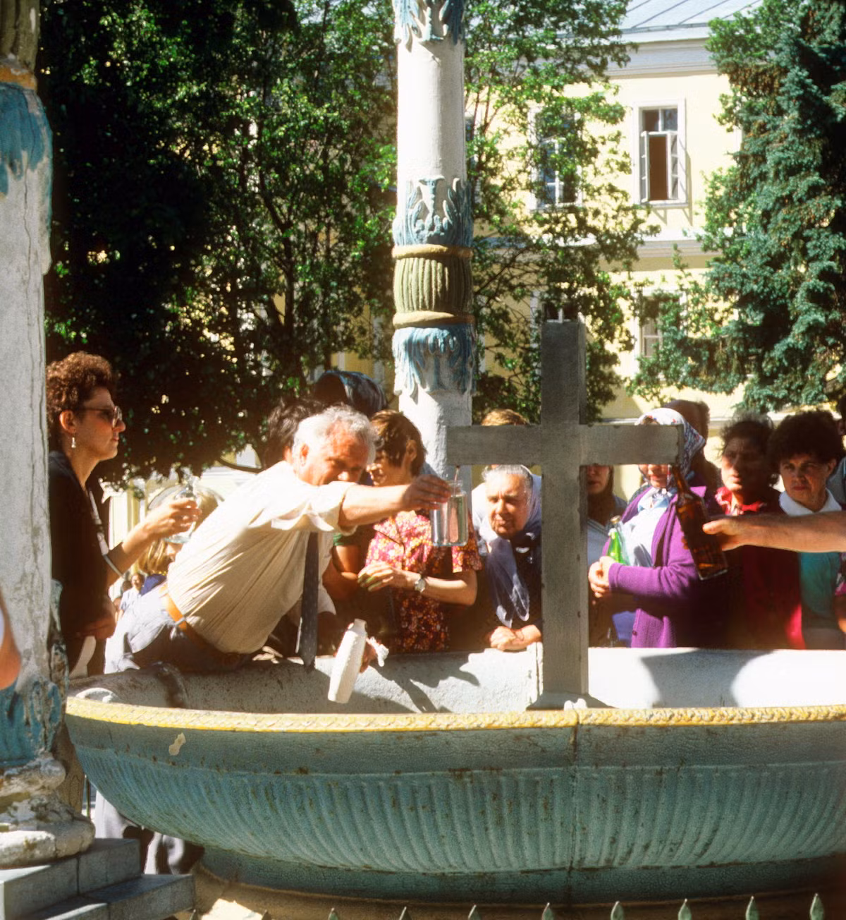 Du khách hứng nước từ vòi phun hình cây thánh giá ở Lavra Thiên Chúa Ba Ngôi.