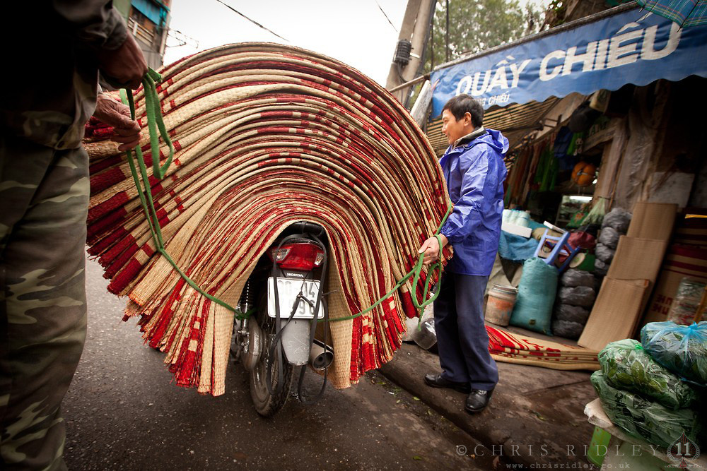 Một người đàn ông đặt số chiếu nhiều nhất có thể lên chiếc xe máy của mình trước khi vận chuyển, ảnh chụp trên phố Hàng Chiếu, Hà Nội năm 2012.