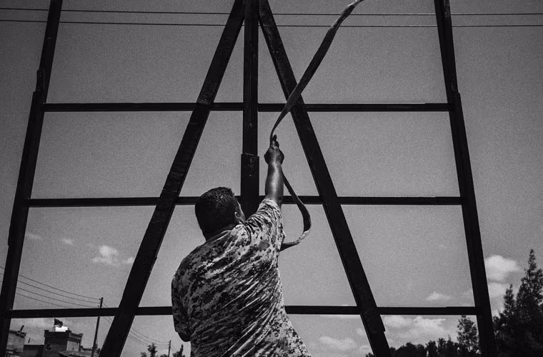 Một chiến binh thân chính phủ Syria đứng gần một khung kim loại và tổ chức khủng bố IS sử dụng để đóng đinh người vô tội.