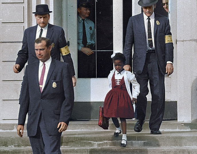 Vào năm 1960, Ruby Bridges trở thành một trong 6 học sinh da đen đầu tiên thi đậu vào trường tiểu học William Frantz vốn dành cho học sinh da trắng ở New Orleans, Mỹ. Tòa án địa phương phải cắt cử 3 cảnh sát người da trắng hộ tống Ruby đến trường. Bức ảnh lịch sử này gợi nhớ về việc phân biệt chủng tộc diễn ra gay gắt ở Mỹ những năm 1900.