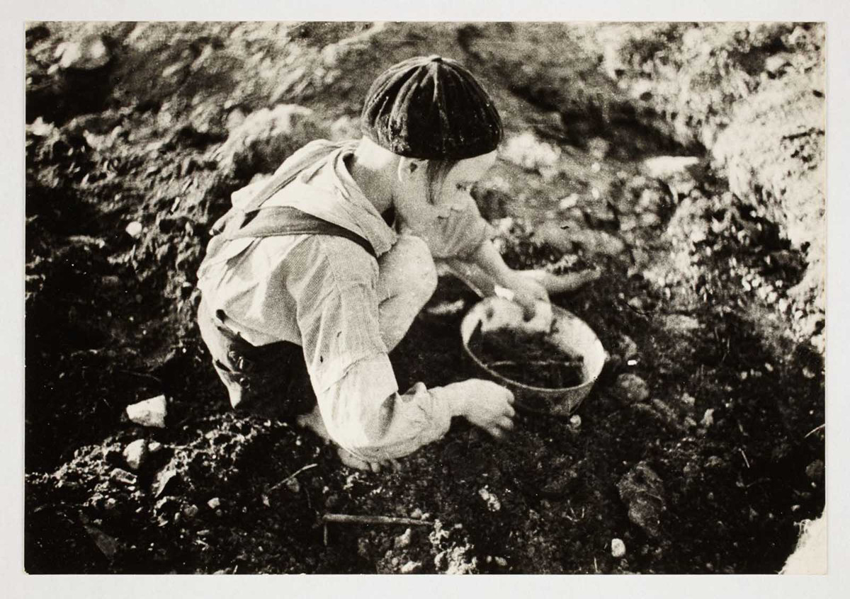 Một cậu bé tìm kiếm thức ăn trên mặt đất.