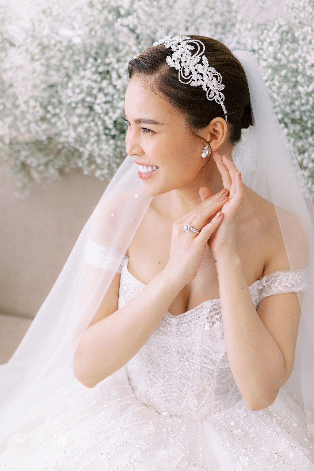 Nữ ca sĩ sinh năm 1989 toát lên vẻ rạng ngời trong thiết kế cưới màu trắng trễ vai, khoe khéo vòng một gợi cảm và bờ vai quyến rũ.