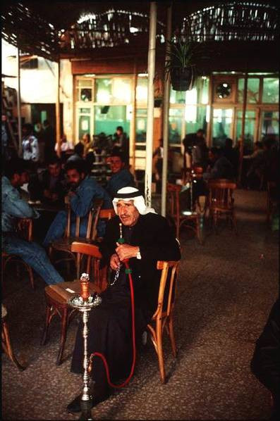 Cụ ông mặc trang phục truyền thống đang hút sisha trong khi những người khác uống cà phê. (Ảnh Ifeng)