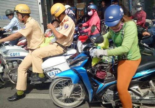 Hình ảnh 2 CSGT người chạy xe mở đường, người vỗ về, cho bé uống nước để đưa khẩn cấp đến bệnh viện cấp cứu đã khiến nhiều người chứng kiến vô cùng xúc động.