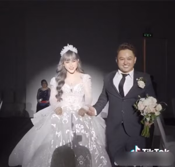 Trong đoạn clip TikTok ghi lại khoảnh khắc "hot girl thị phi" sánh đôi bên chồng, chú rể điển trai trong bộ áo vest đen lịch lãm, cả hai tay trong tay cùng dắt nhau vào lễ đường.