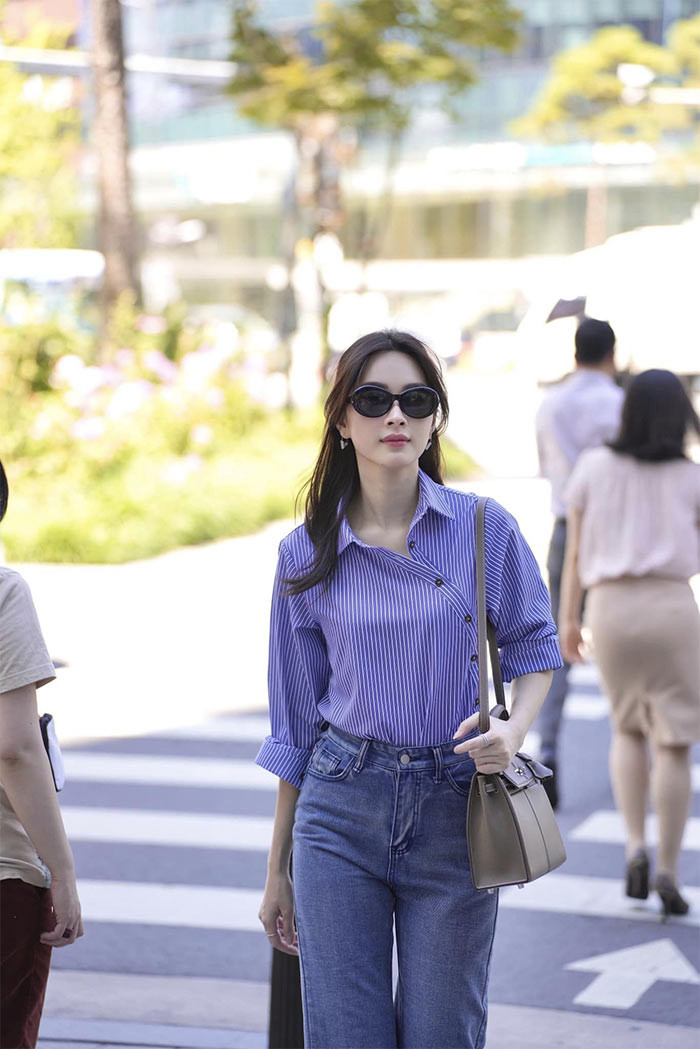 Hoa hậu Việt Nam 2012 ăn mặc rất giản dị với trang phục quần jeans và áo sơ mi kẻ màu xanh.