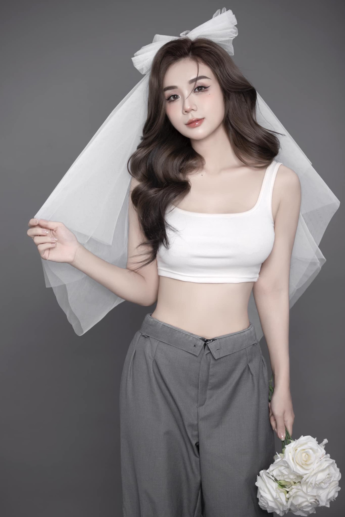 Trong loạt ảnh mới nhất, Bảo Ngọc diện suit kết hợp với bra, đầu đội khăn voan, tay cầm bó hoa hồng trắng "tông xuyệt tông".