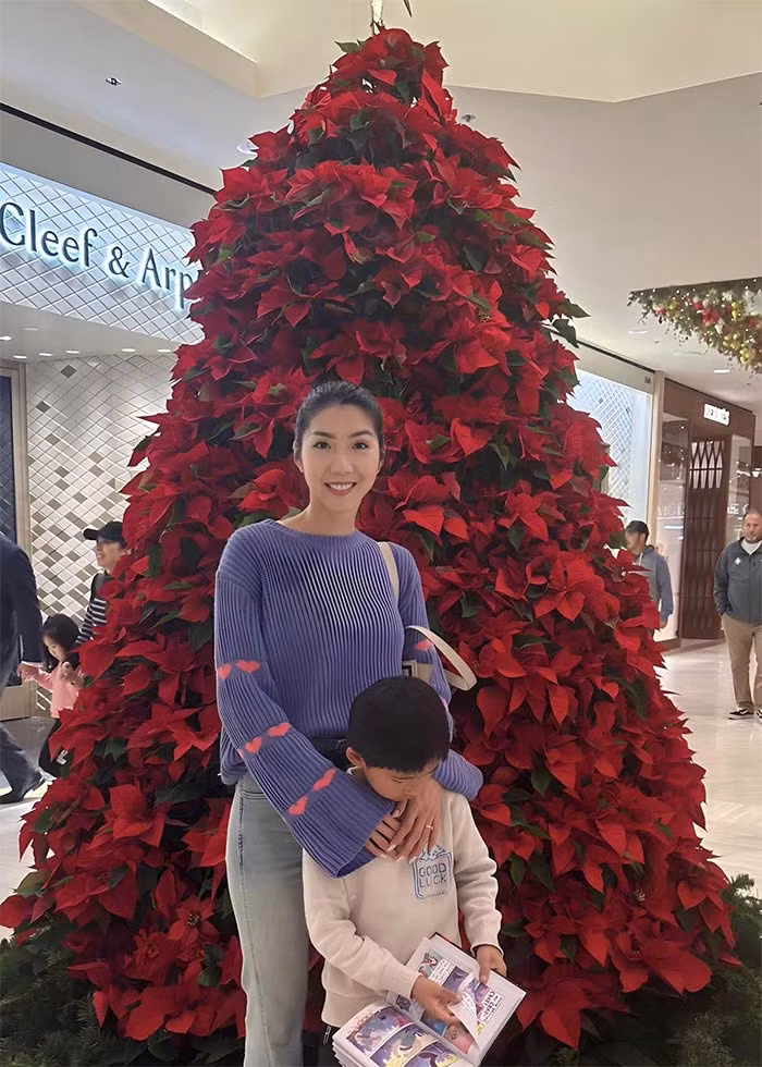 Hai mẹ con Ngọc Quyên chụp ảnh với cây thông Noel trong một trung tâm thương mại.