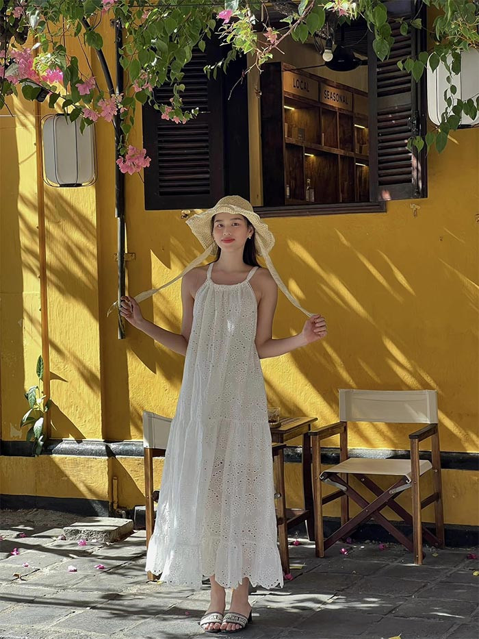 Váy hai dây màu trắng, dép lê, Đỗ Thị Hà giản dị trong một chuyến du lịch.