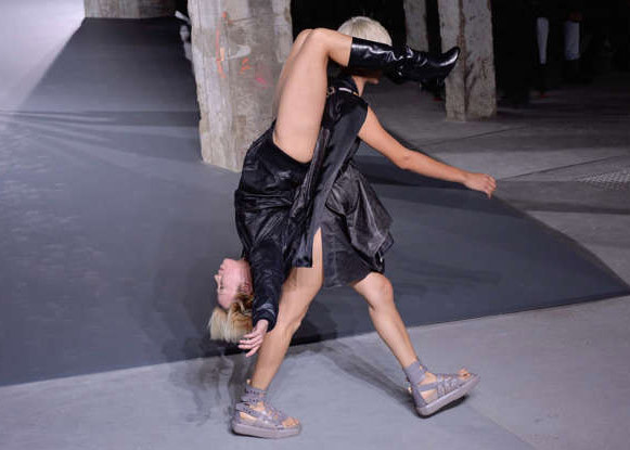 Một người mẫu phải cõng một người mẫu khác khi mặc trang phục trong bộ sưu tập mới của Rick Owens rồi sải bước trên sàn catwalk. (Ảnh: Getty Images)