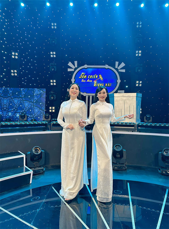 Nữ nghệ sĩ sinh năm 1966 tự tin mặc áo dài trắng, đọ sắc với bạn thân Hồng Đào trên sân khấu một chương trình.