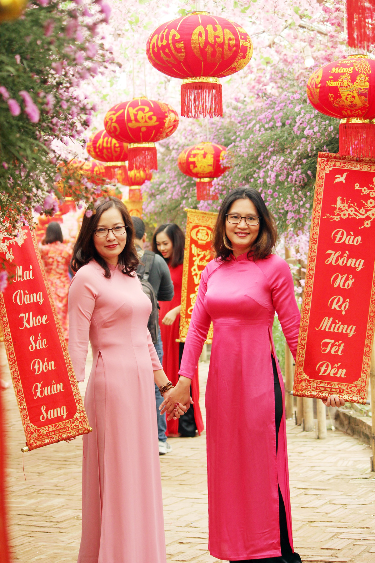 Những tà áo dài duyên dáng được chị em lựa chọn làm trang phục chủ đạo để chụp với các câu đối đỏ.