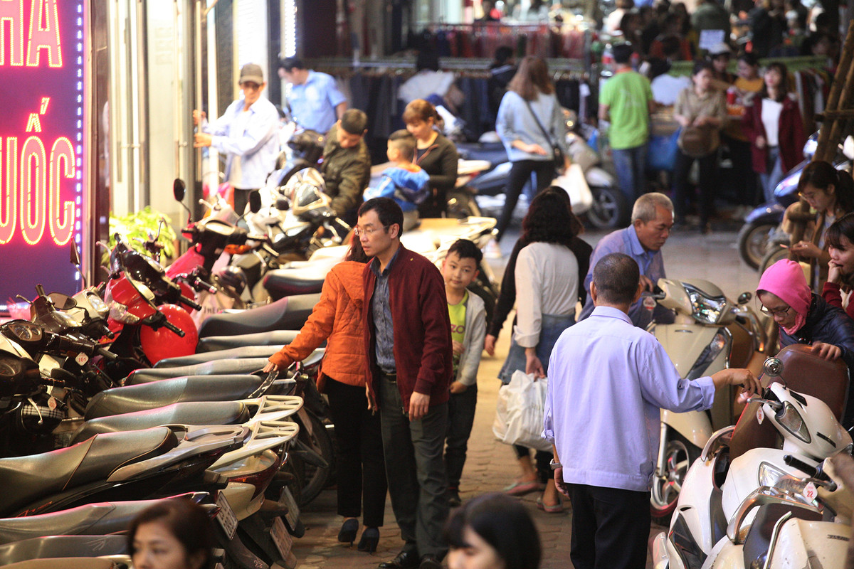 Vỉa hè ở phố Chùa Bộc bị "chiếm dụng" để làm chỗ để xe máy, người đi bộ phải luồn lách tìm lối thoát.