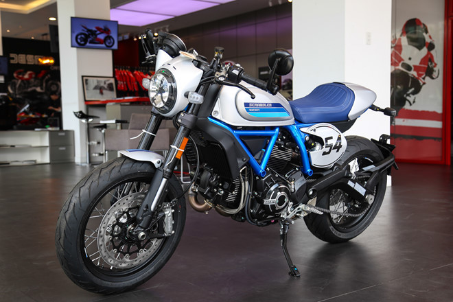 Phiên bản Ducati Scrambler Cafe Racer 2019 với dàn áo xanh-xám mờ bắt mắt. Xe kế thừa giá trị từ những mẫu xe đầu tiên đời 1962, đồng thời cũng thừa hưởng nhiều đặc điểm từ đàn anh Scrambler 1100.