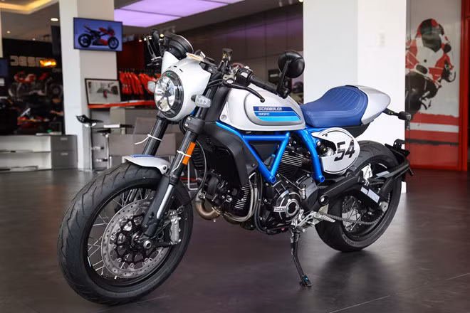Phiên bản Ducati Scrambler Cafe Racer 2019 với dàn áo xanh-xám mờ bắt mắt. Xe kế thừa giá trị từ những mẫu xe đầu tiên đời 1962, đồng thời cũng thừa hưởng nhiều đặc điểm từ đàn anh Scrambler 1100.