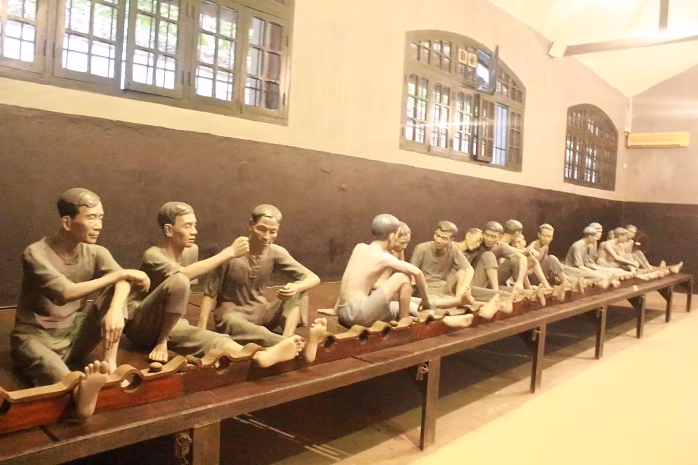 Các tù chính trị đều bị cùm chân, ngồi trên một phản gỗ.